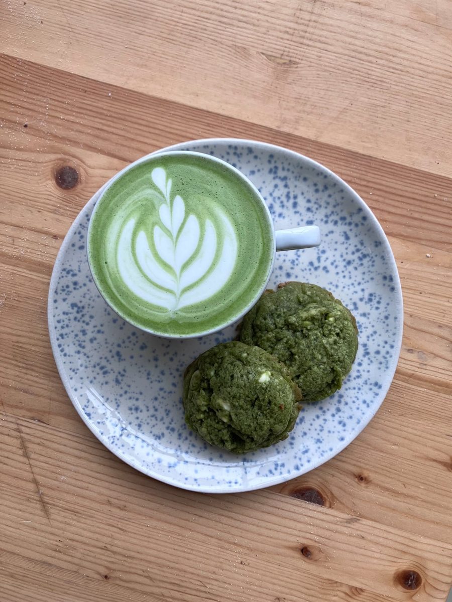 Matcha latte s obrázkem v pěně a dvě matcha sušenky